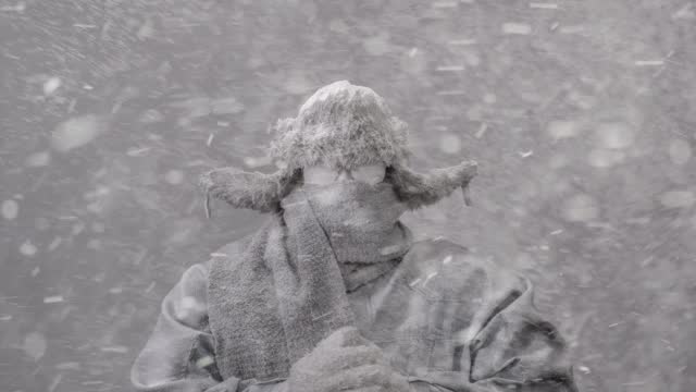 Frozen man in parka, trapper’s hat and scarf in a blizzard