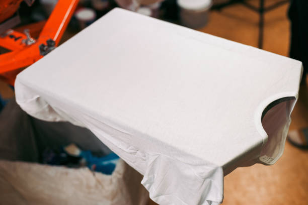 istock white t-shirt is ready for printing. creating print on t-shirt in workshop. serigraphy production. silkscreen printing selective focus close-up photo 1437023055