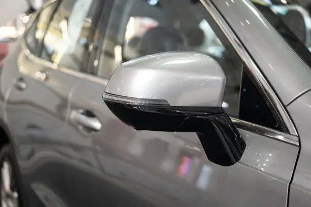 Side mirror of the modern luxury car with turning light signal, 360 camera and blind spot camera technology built-in. Vehicle part object photo, selective focus.
