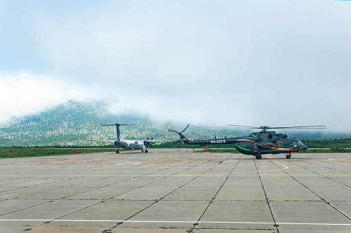 Yuzhno-Kurilsk, Russia - August 03, 2022: helicopter and plane at the airport of Kunashir island preparing for takeoff