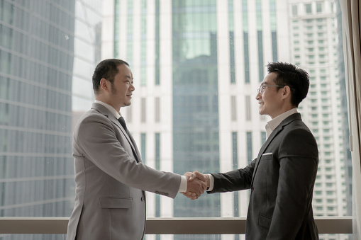 2 Asian Businessmen shaking hands in conference room