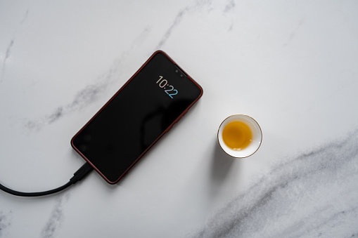 Charging mobile phone and a cup of Chinese tea