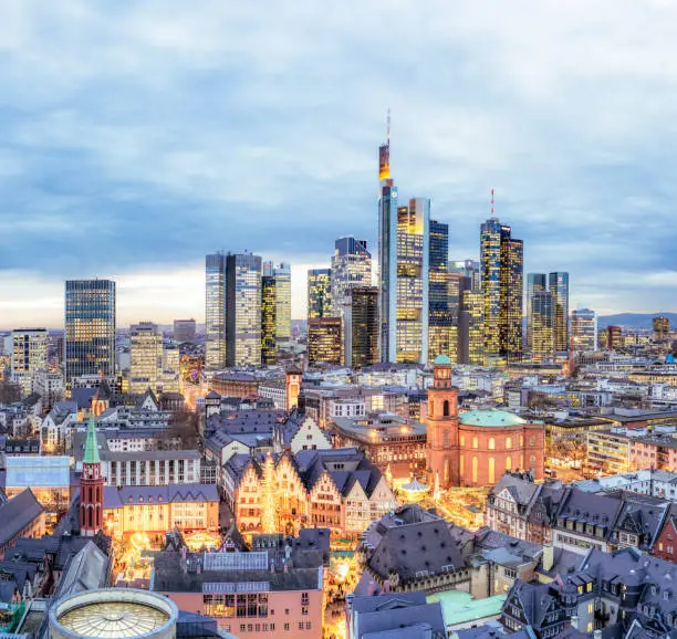 A view over Frankfurt's city centre, with the annual Christmas Markets and attractions in the foreground, and the city's modern business skyline on the horizon at dusk.
