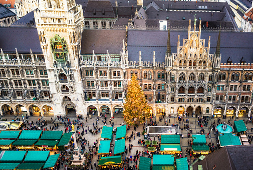 Christmas decorations, a large Christmas tree, and people shopping at market stalls in central Munich, during December.