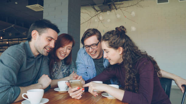 istock Young people are watching smartphone screen discussing photos and laughing during lunch break in cafe. Friendship, modern technology and modern lifestyle concept. 1437031353