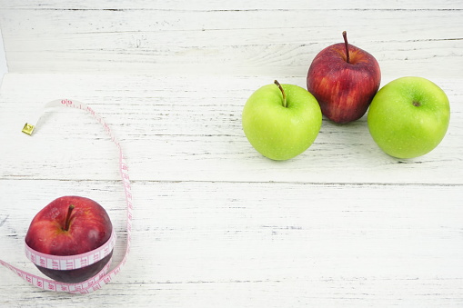 Green and Red Apples with measuring tape over wooden background. Healthy Food Lifestyle Concept