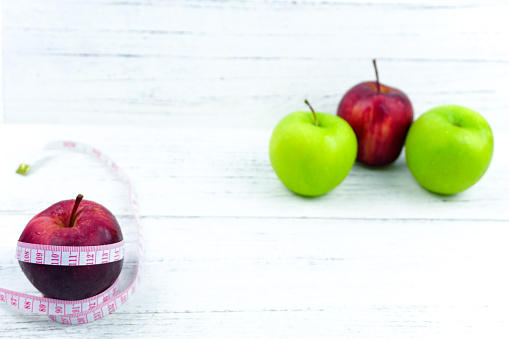 Green and Red Apples with measuring tape over wooden background. Healthy Food Lifestyle Concept