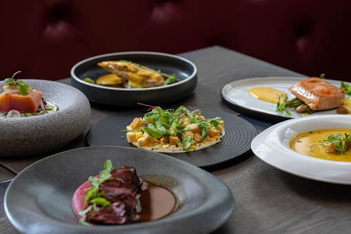 A closeup of tasty multiple cooked dishes in different ceramic plates on the table
