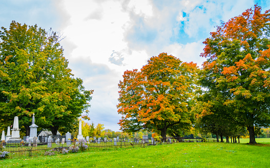 cemetery with white gravestones with bright autumn colors of fall foliage