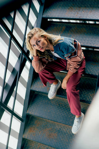 istock Cheeky modern woman looking at camera while sitting on steps 1437040246