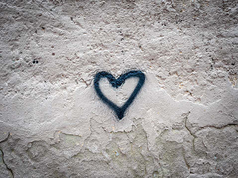 a heart drawn with a spray paint on an old damaged wall