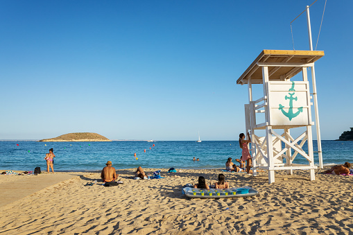 Magaluf, Majorca, Spain - September the 19th 2022: Tourists relaxing on the beach in Magaluf, resort town on the Spanish island of Majorca, with island Sa Porrassa in the background