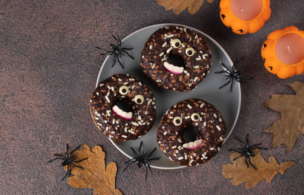 istock Halloween festive donuts with eyes and teeth on brown background, Top view 1437044806