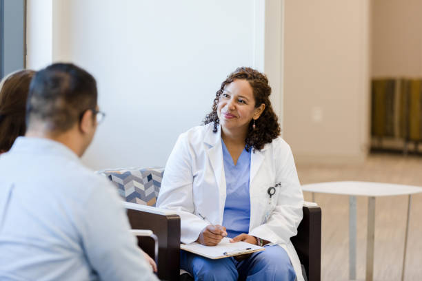 Mid adult doctor listens attentively to unrecognizable couple stock photo