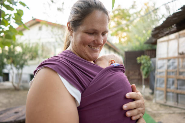 Beautiful mother with her son in sling back yard