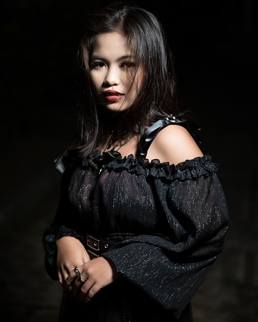 A Filipina in a vampire costume on a black background - concept of Halloween