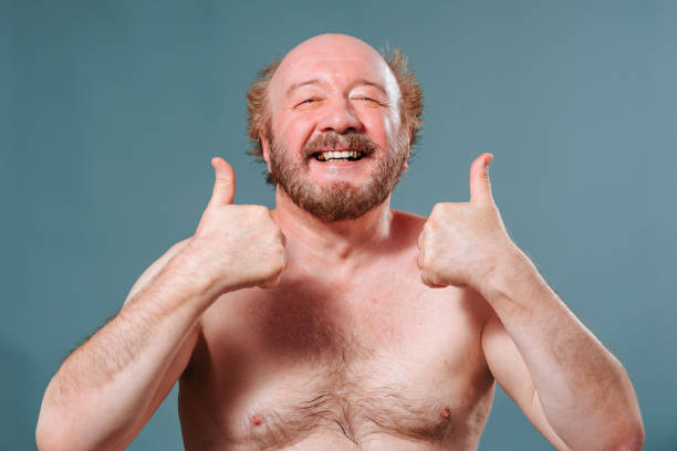 istock Front view an aged senior man in the studio on a blue background shows a gesture thumb up smile joy. 1437067798