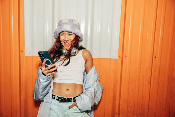 mujer enviando mensajes de texto en el móvil fuera de un club el sábado por la noche - street style fotografías e imágenes de stock