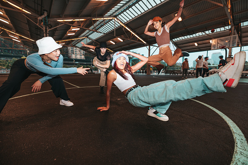 Group of four urban style professional dancers dressed with street-style clothes performing in the city streets in New York.