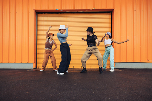 Group of four young females professional dancers dressed with urban clothes performing in the city streets in New York.