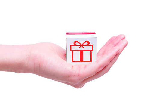 Miniature gift box with pink tape in hand isolated on white background. Creative gifts shop delivery concept.