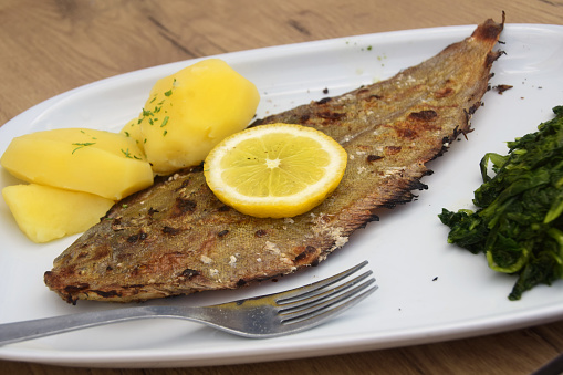Traditional Portuguese grilled sole dinner served with spinach and boiled potatoes.