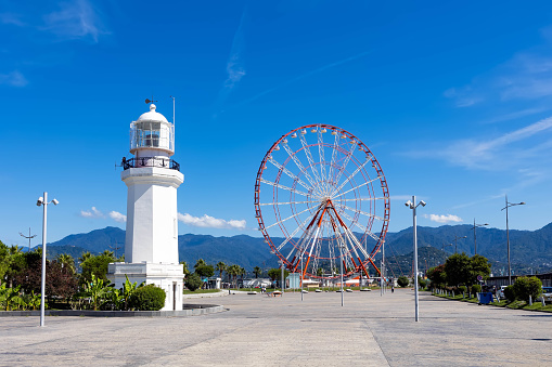 Batumi, Georgia - September 15, 2022: View of the historical city center and the Black Sea coast on a sunny summer day. Batumi ferris wheel and Sukhumi lighthouse.