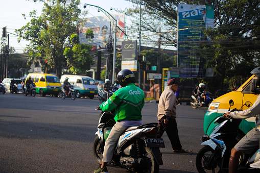Bandung, West Java, Indonesia - July 31, 2022: Indonesian Grab driver is waiting in a crossroad in Bandung in the morning