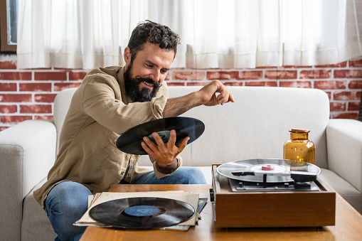 A hipster man is cleaning a vinyl record