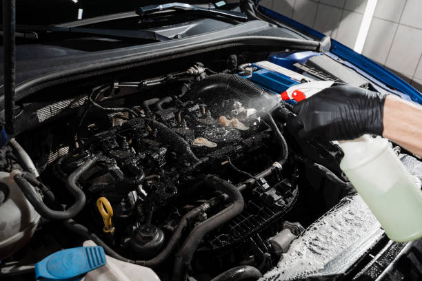 istock Spraying detergent on car engine. Washing car engine with spray and detergent in detailing auto service. Detailing cleaning motor from dust and dirt. 1437081613