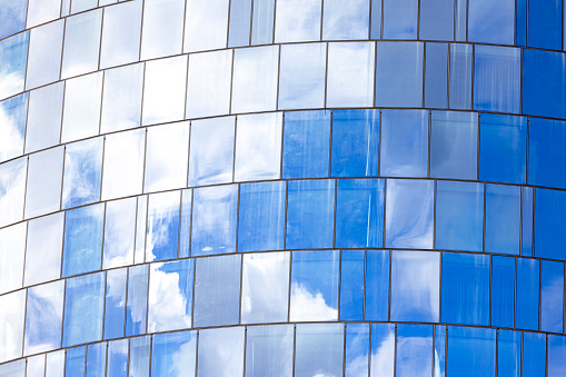Closeup glass wall of office building with reflection of sky, background with copy space, full frame horizontal composition
