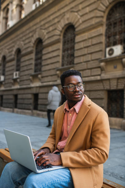 istock Portrait of a black man sitting outside using a laptop 1437087607