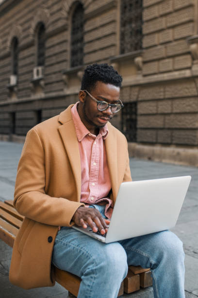 istock Portrait of a black man sitting outside using a laptop 1437087608