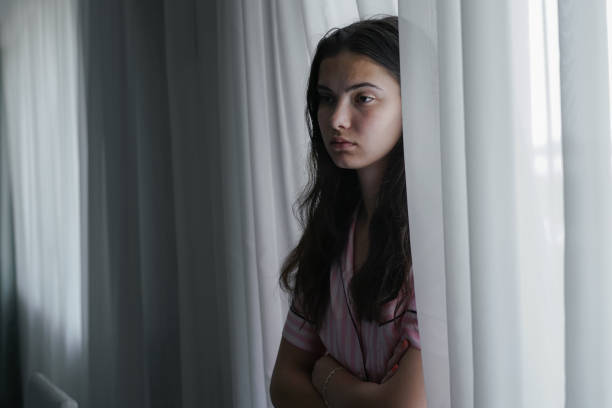 samotna, nieszczęśliwa nastolatka stojąca w domu pod oknem - teenager dark pensive emotional stress zdjęcia i obrazy z banku zdjęć