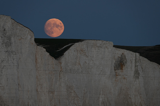 Full Hunters moon rising over the Seven Sisters cliffs on the South Downs, Sussex, UK