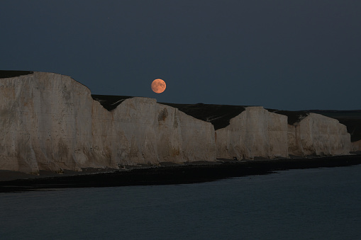 Full Hunter's moon rising over the Seven Sisters cliffs on the South Downs, Sussex, UK