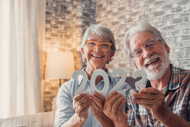 portrait of couple of two old pensioners holding together numbers of 2023 at home. close up of new year numbers, celebrating and goals for new life concept. - 80 year old imagens e fotografias de stock