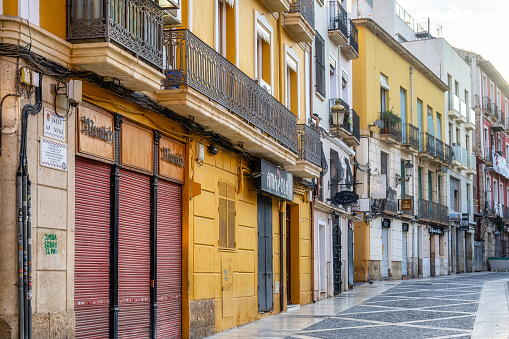 Alicante, Spain - September 29, 2022: An empty sidewalk in an urban area. Story buildings with balconies line one side of the walkway, and no people are on the scene.