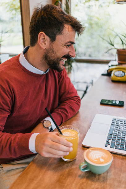 istock Young man having a video call on his laptop while sitting in a coffee shop 1437100143