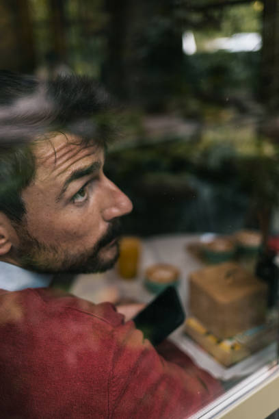 istock Young man looking through a coffee shop window 1437100190