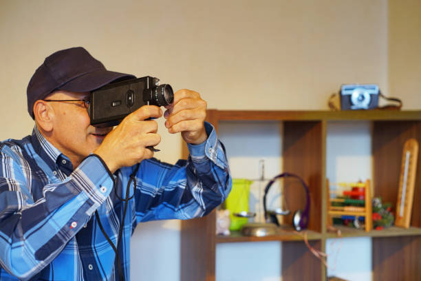 Using a Super 8 Movie Camera A man use a Super 8 film camera in his home. vintage amateur movie camera stock pictures, royalty-free photos & images