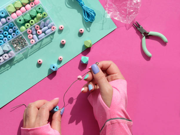istock Handmade jewelry. Box with beads, hands with tools. Making handmade jewelry for yourself or as self made gifts. Flat lay, top view on split pink and mint green paper background. 1437102042