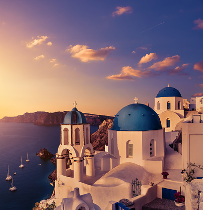 Sunset over Oia in Santorini. Local church with blue cupola in Oia village, Santorini island, Greece. Toned image, pink and purple. Beautiful Greek island scenery. Panoramic image, square composition.