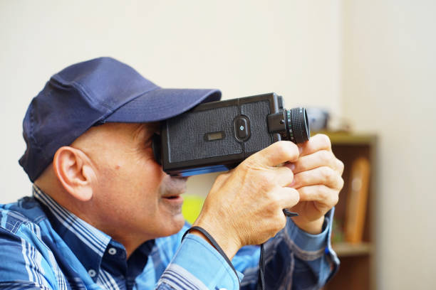 Using a Super 8 Movie Camera A man use a Super 8 film camera in his home. vintage amateur movie camera stock pictures, royalty-free photos & images