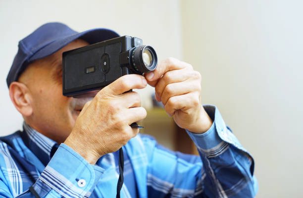Using a Super 8 Movie Camera A man use a Super 8 film camera in his home. vintage amateur movie camera stock pictures, royalty-free photos & images