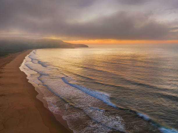 istock Peaceful sunrise over the ocean with small waves and clouds 1437117388