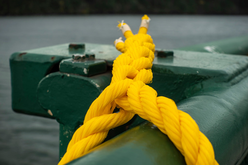 Close up, selective focus on a yellow, knotted rope on the green railing of a Washington State Ferry