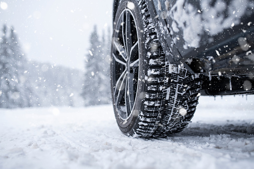 Close-up low angle shot of car tyre on a snowy road in winter.