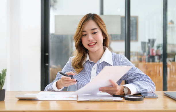 istock Young businesswoman working with document while sitting in modern coffee shop. 1437132680