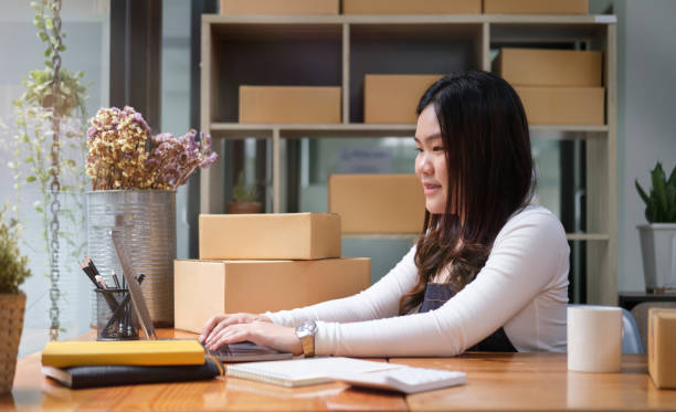 istock Asian woman seller using laptop computer, checking order on internet at his home office. Startup small business, Online selling, E-commerce concept. 1437134411